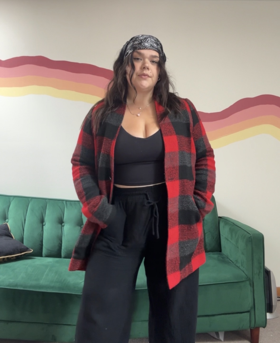 Brooklyn in a red plaid coat in front of a painted rainbow wall